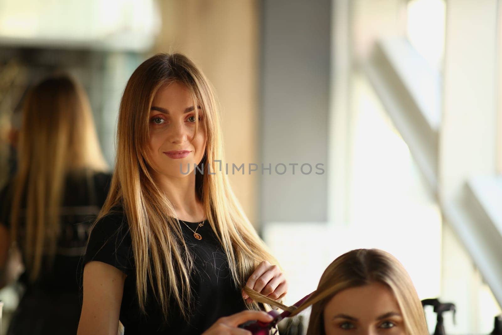 Woman hairdresser makes haircut to woman in beauty salon by kuprevich