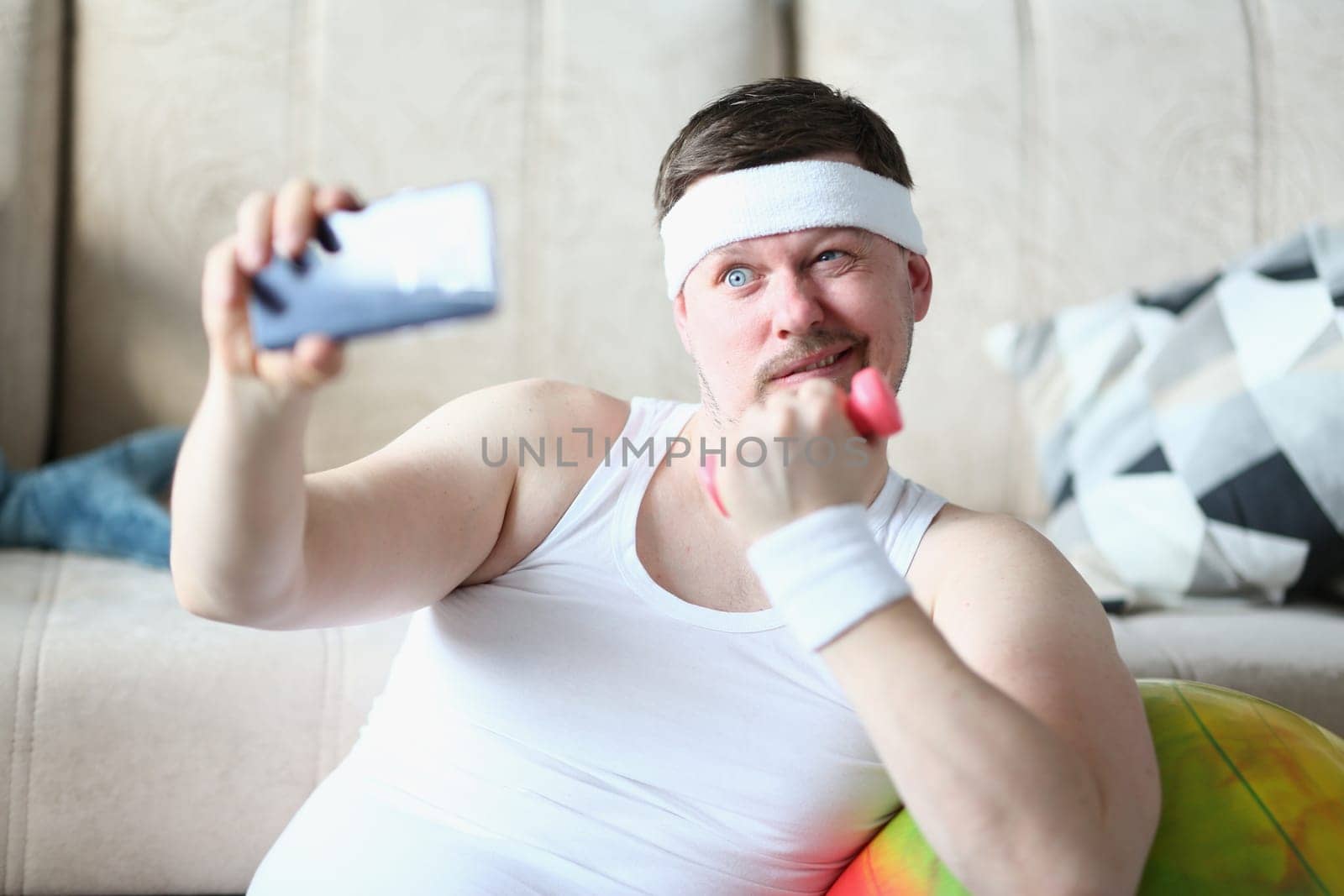 Young man takes selfie with dumbbells in hands by kuprevich