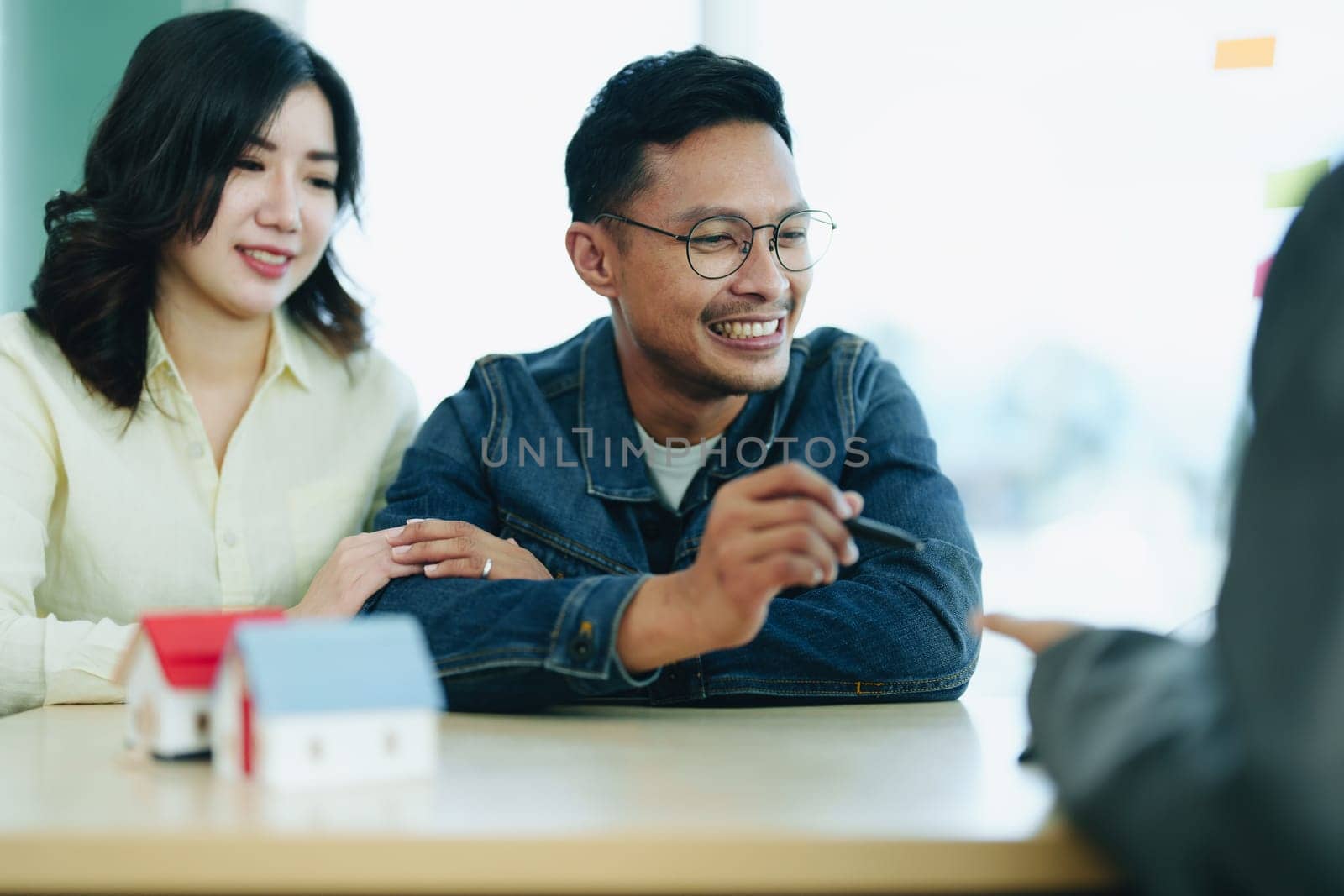 Guarantee Insurance Sign a contract, couple a smiling couple is signing a contract to invest in real estate with the Mortgage officer with the bank.