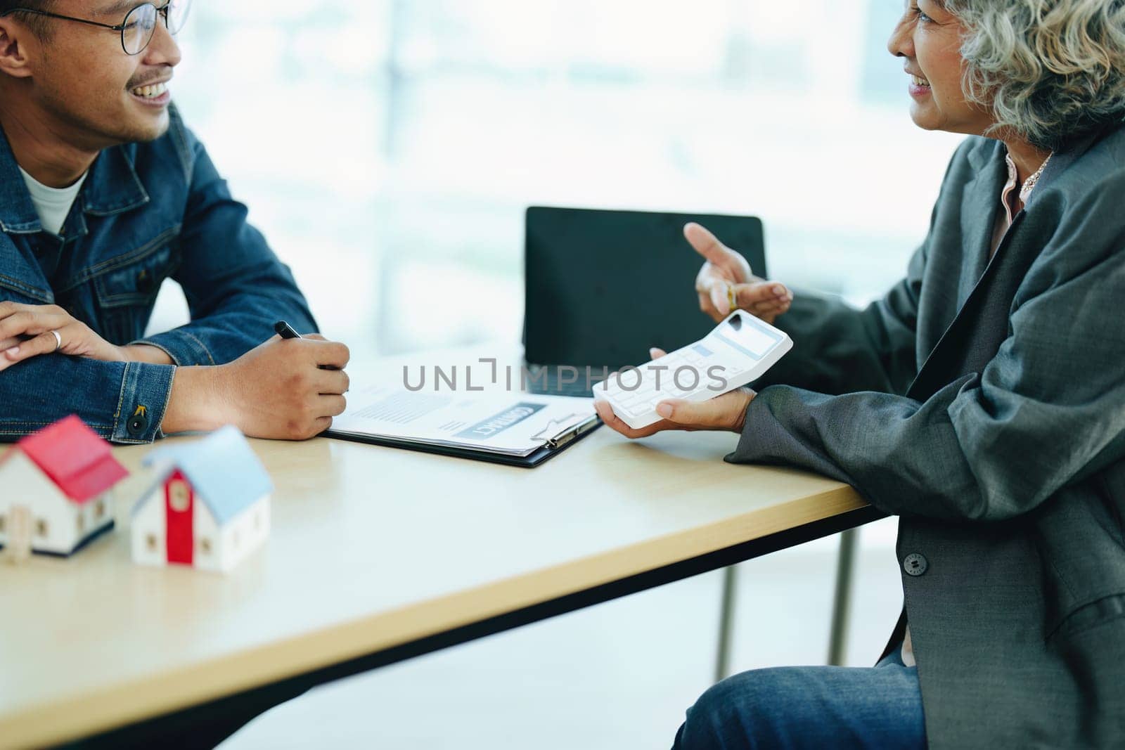 Guarantee Insurance Sign a contract, couple a smiling couple is signing a contract to invest in real estate with the Mortgage officer with the bank by Manastrong