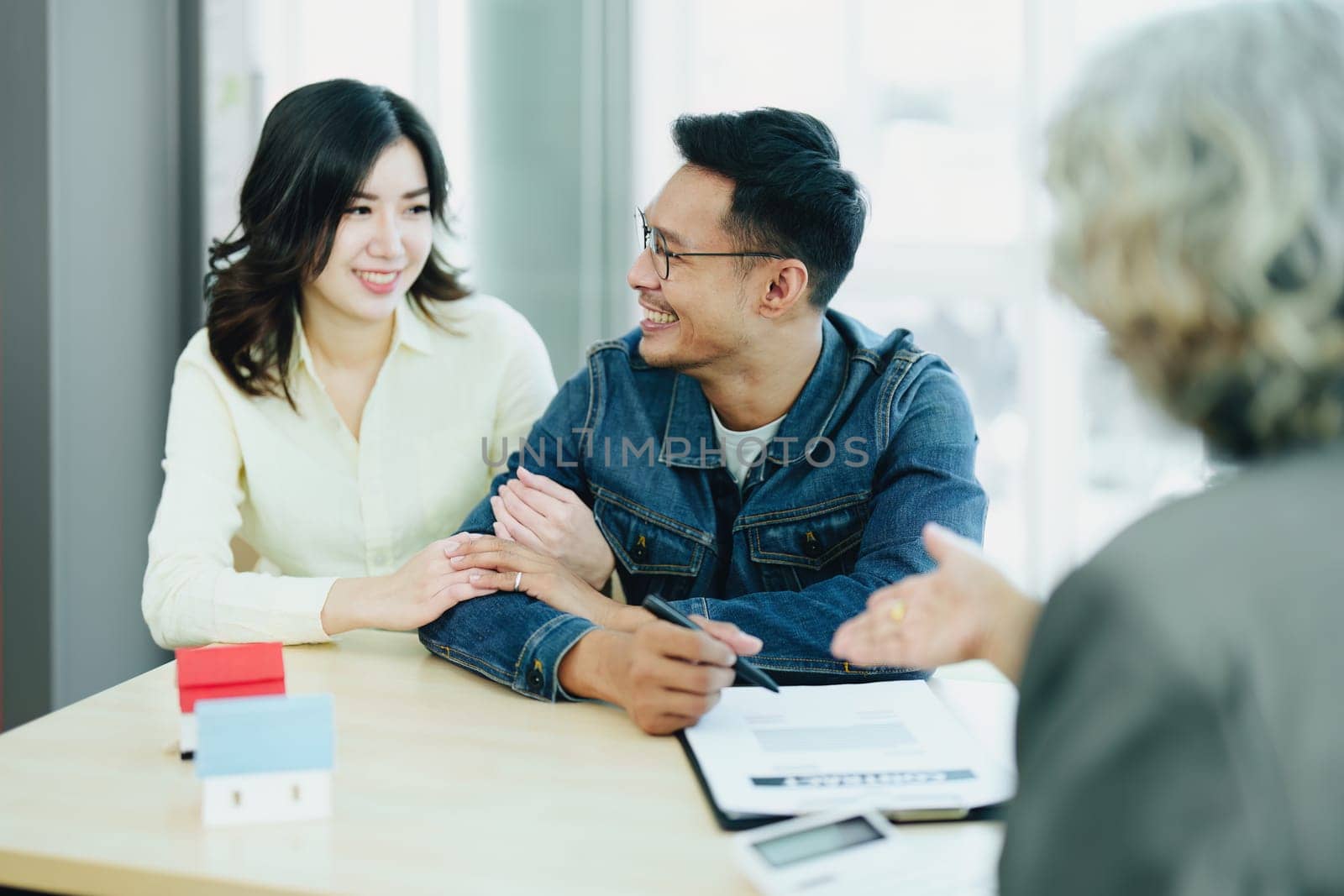 Guarantee Insurance Sign a contract, couple a smiling couple is signing a contract to invest in real estate with the Mortgage officer with the bank.