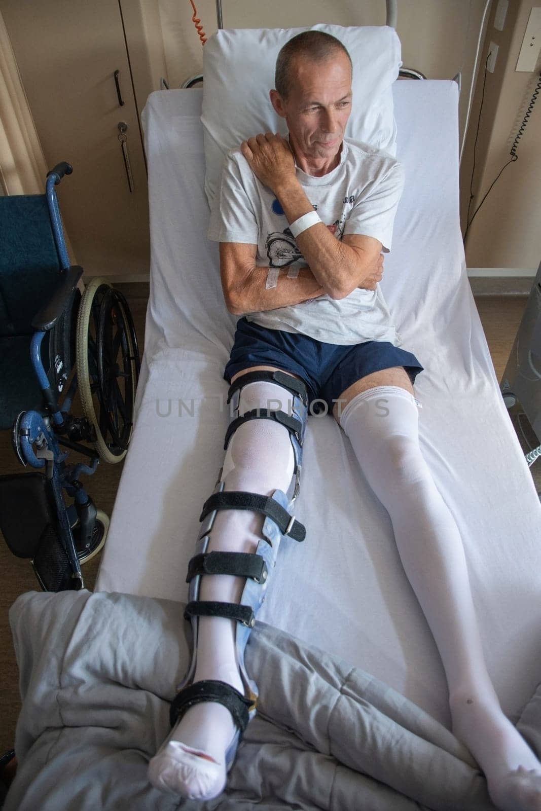 a man with a broken leg in an orthese in bed in a clinic after an accident, High quality photo