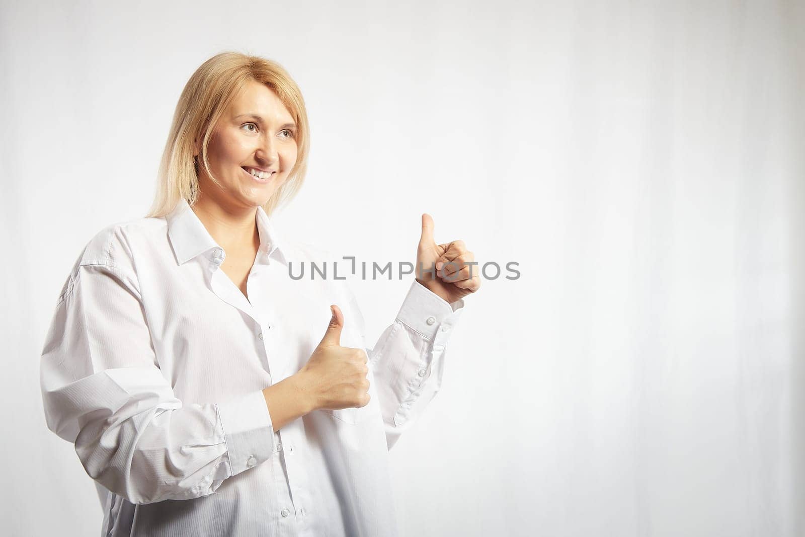 Portrait of a pretty blonde smiling woman posing on white background. Happy girl model in white shirt in studio. Lady winner is joyfull. Copy space