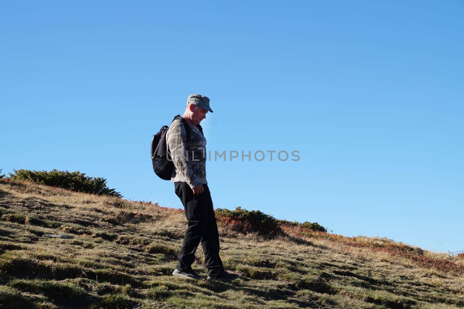 a man with a backpack walks along a mountain path by Annado