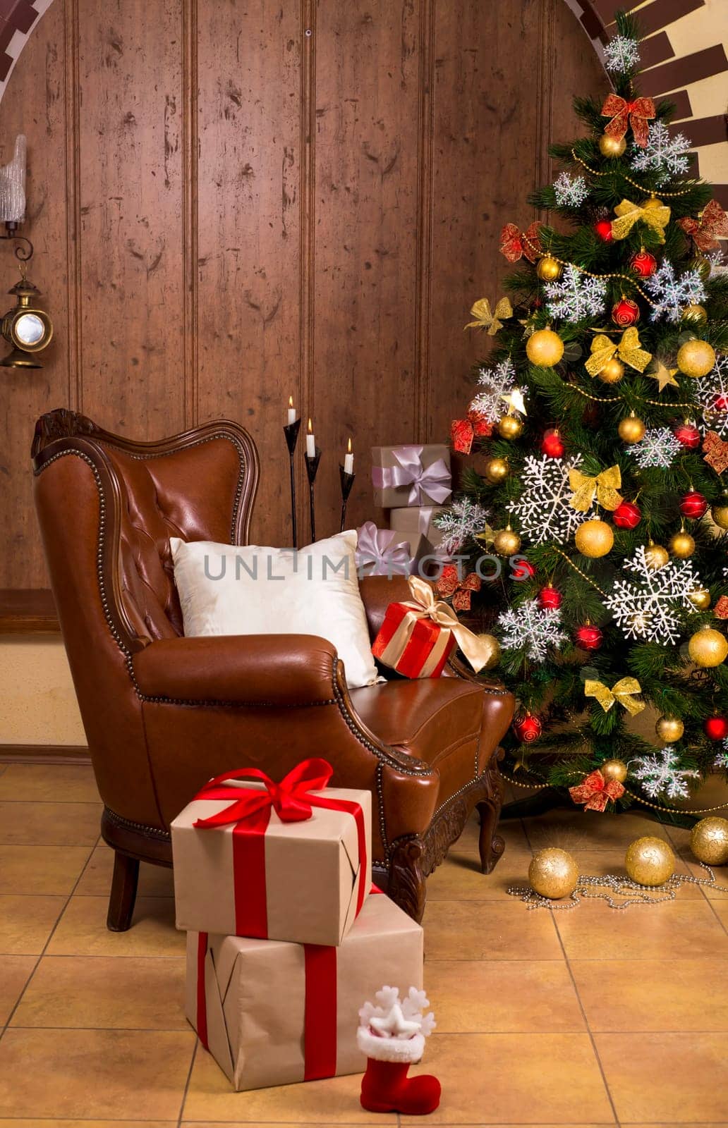The living room in the house is decorated for Christmas. Christmas tree decorated for the holiday and a lot of gifts next to it. Retro armchair in the house. by aprilphoto
