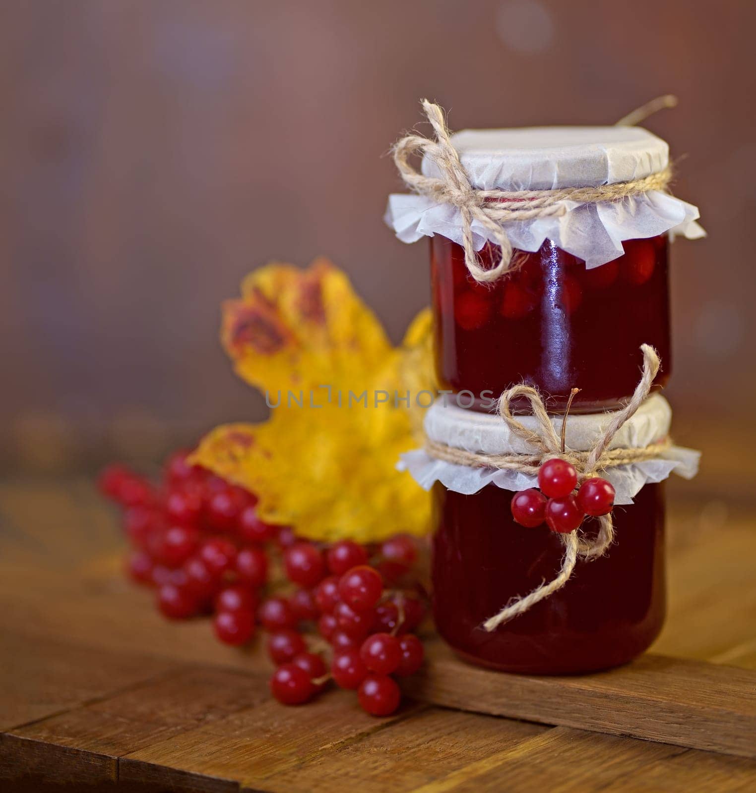 Viburnum fruit jam in a glass jar on a wooden table, preparations for the winter