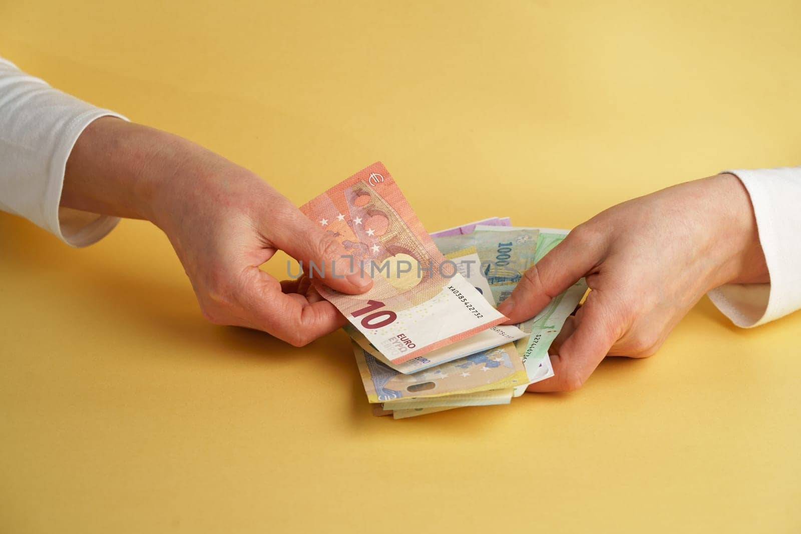 Euro Money. Female hands holding euro banknotes on a yellow background.