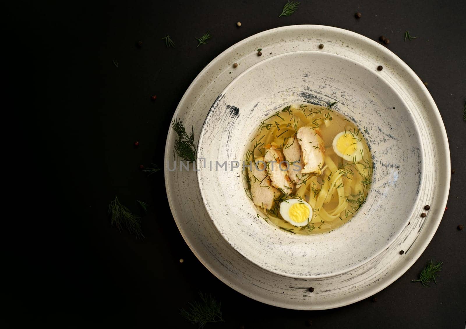 chicken soup with vermicelli and vegetables close-up in a bowl on a wooden tray on the table. horizontal top view from above by aprilphoto