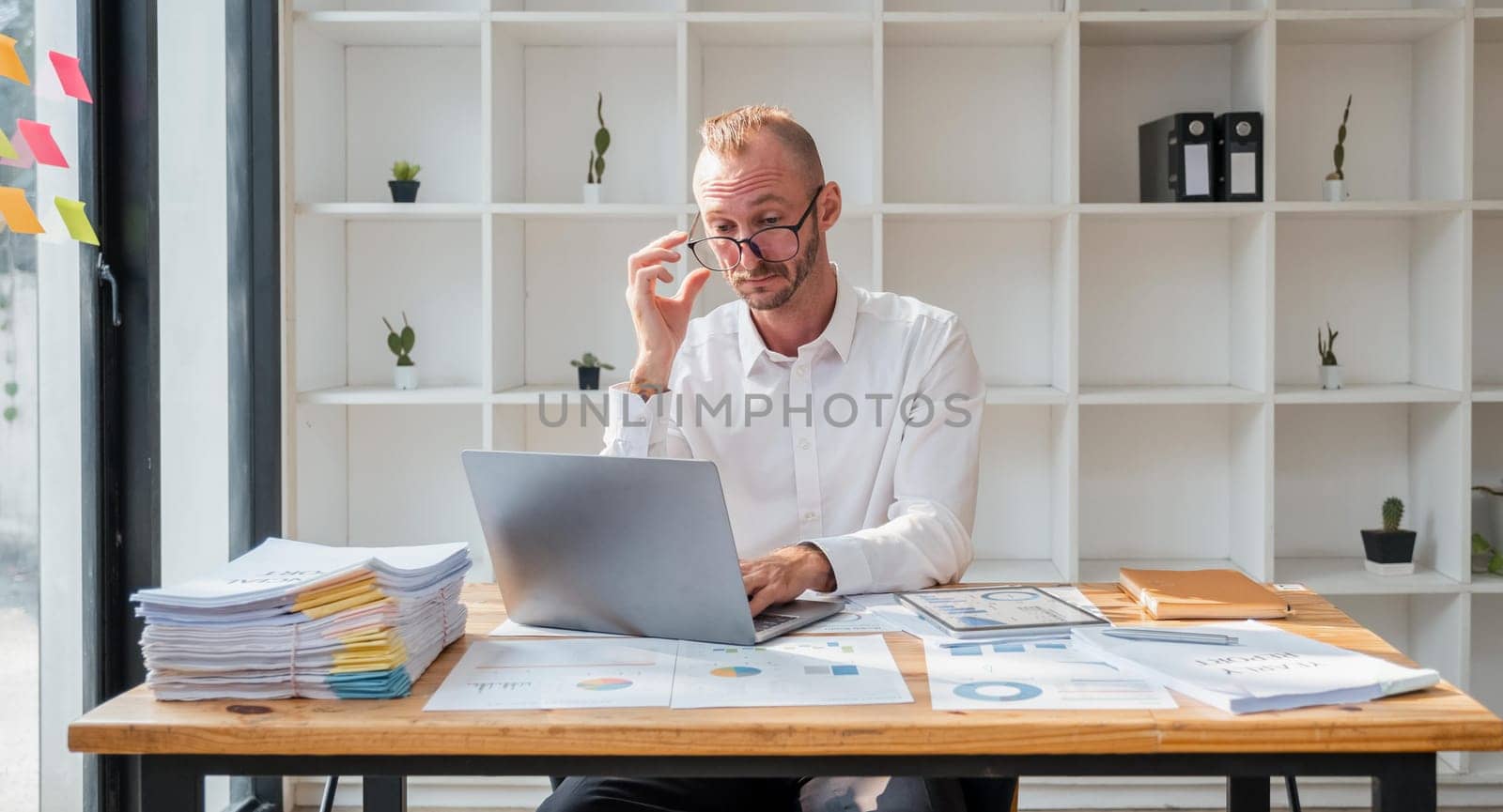 Young business man working at office with laptop and papers on desk by nateemee
