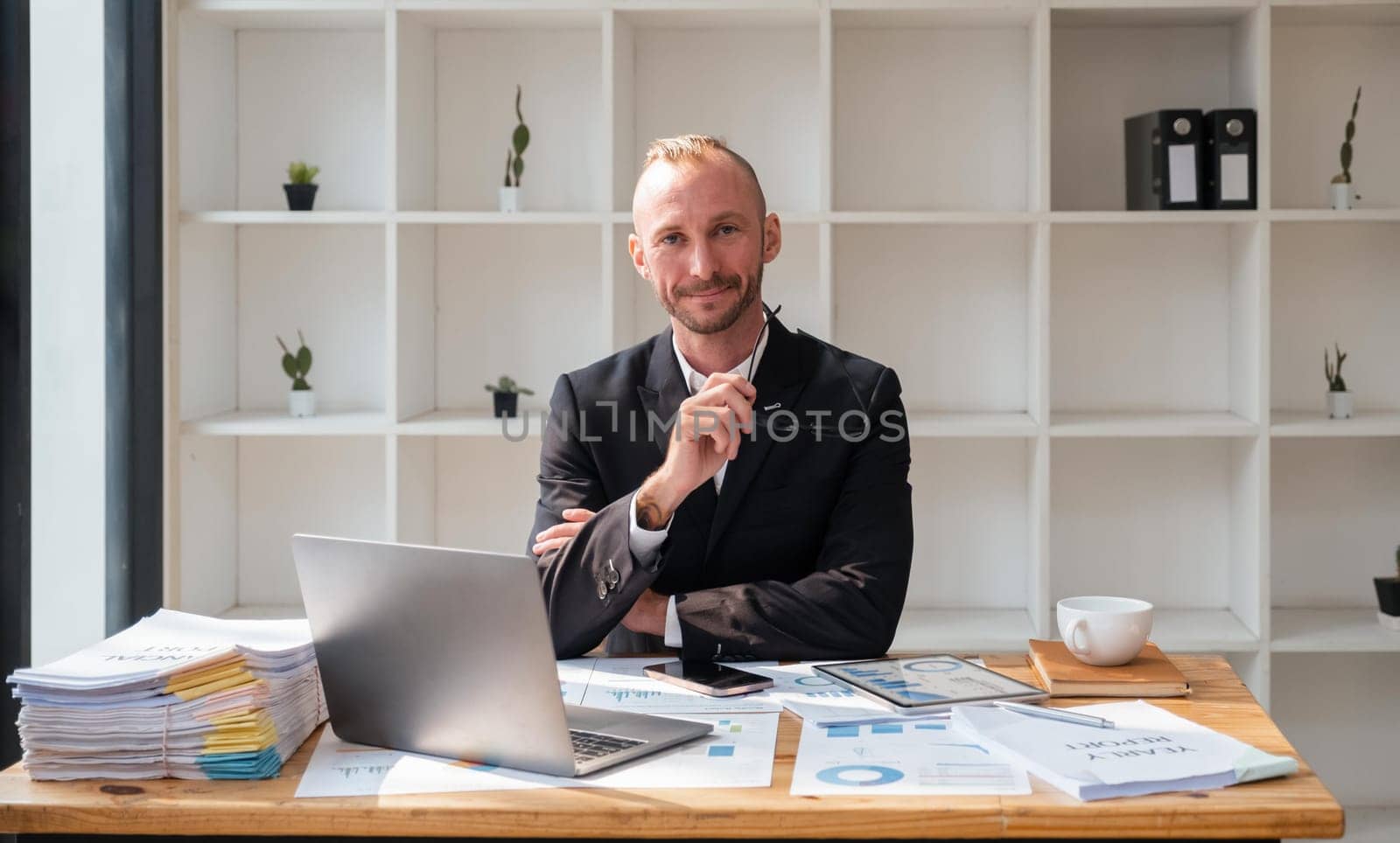 Portrait of attractive smiling young business man sitting in office and looking at camera.