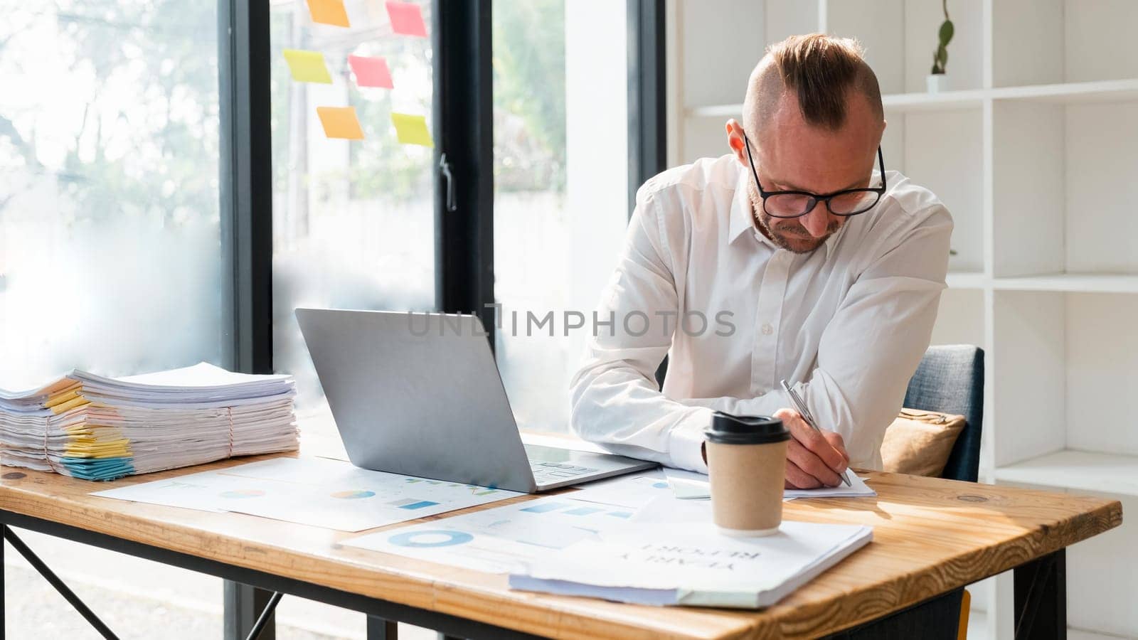 business man in casual making notes in notepad while sitting in his office.