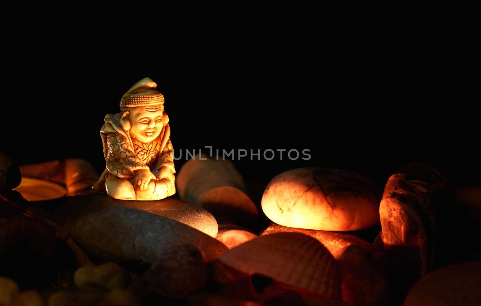A serene calm monk meditates by the fire in darkness of the night among stones by jovani68