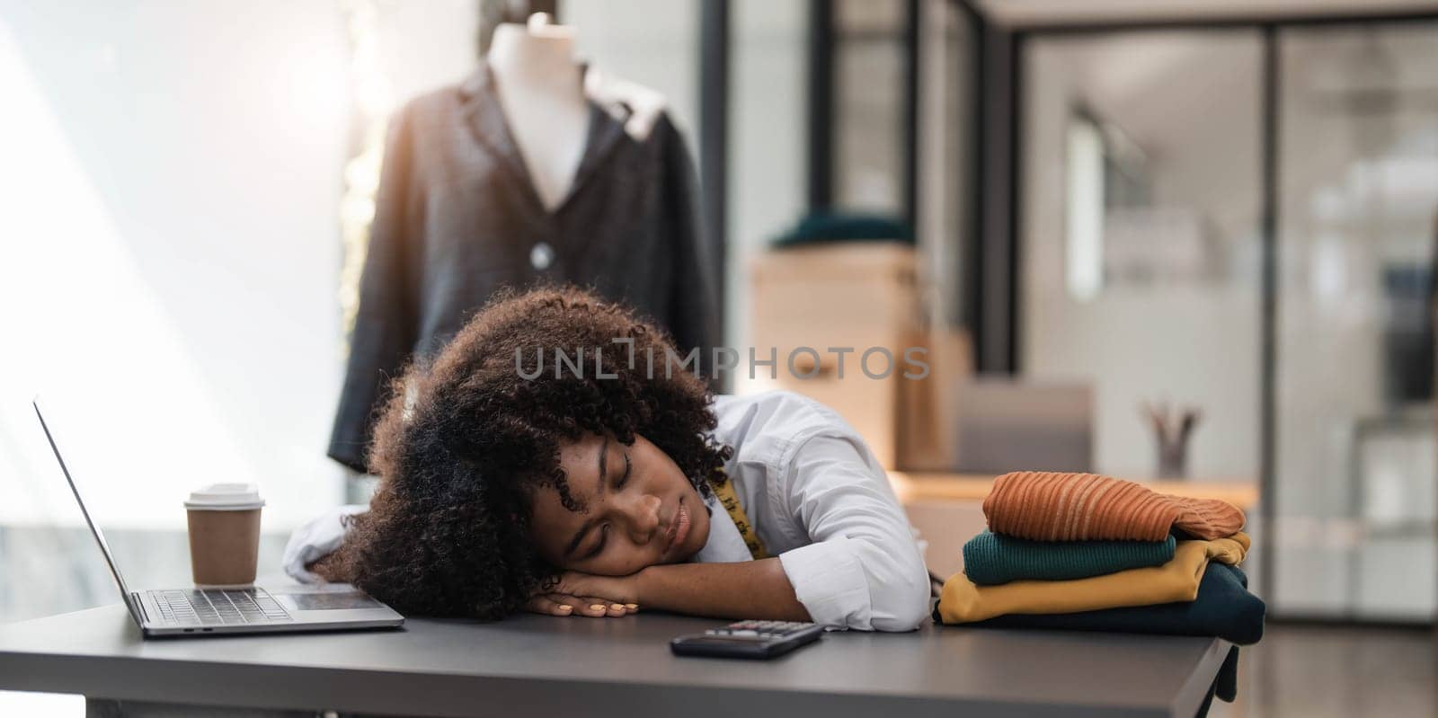 People tailor working in fashion design concept. Young adult asian designer woman tried and sleeping at workshop table. Background in business start up studio dressmaker. by wichayada