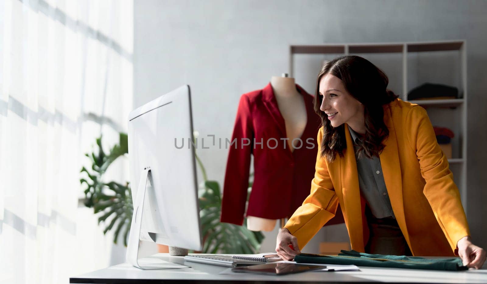 Portrait of young beautiful asian woman fashion designer stylish stand and working with color samples.Attractive young asian girl working with colorful fabrics at fashion studio by wichayada