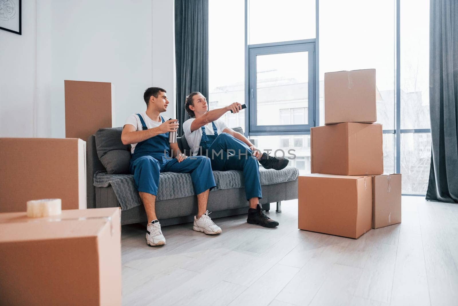 Two young movers in blue uniform working indoors in the room.