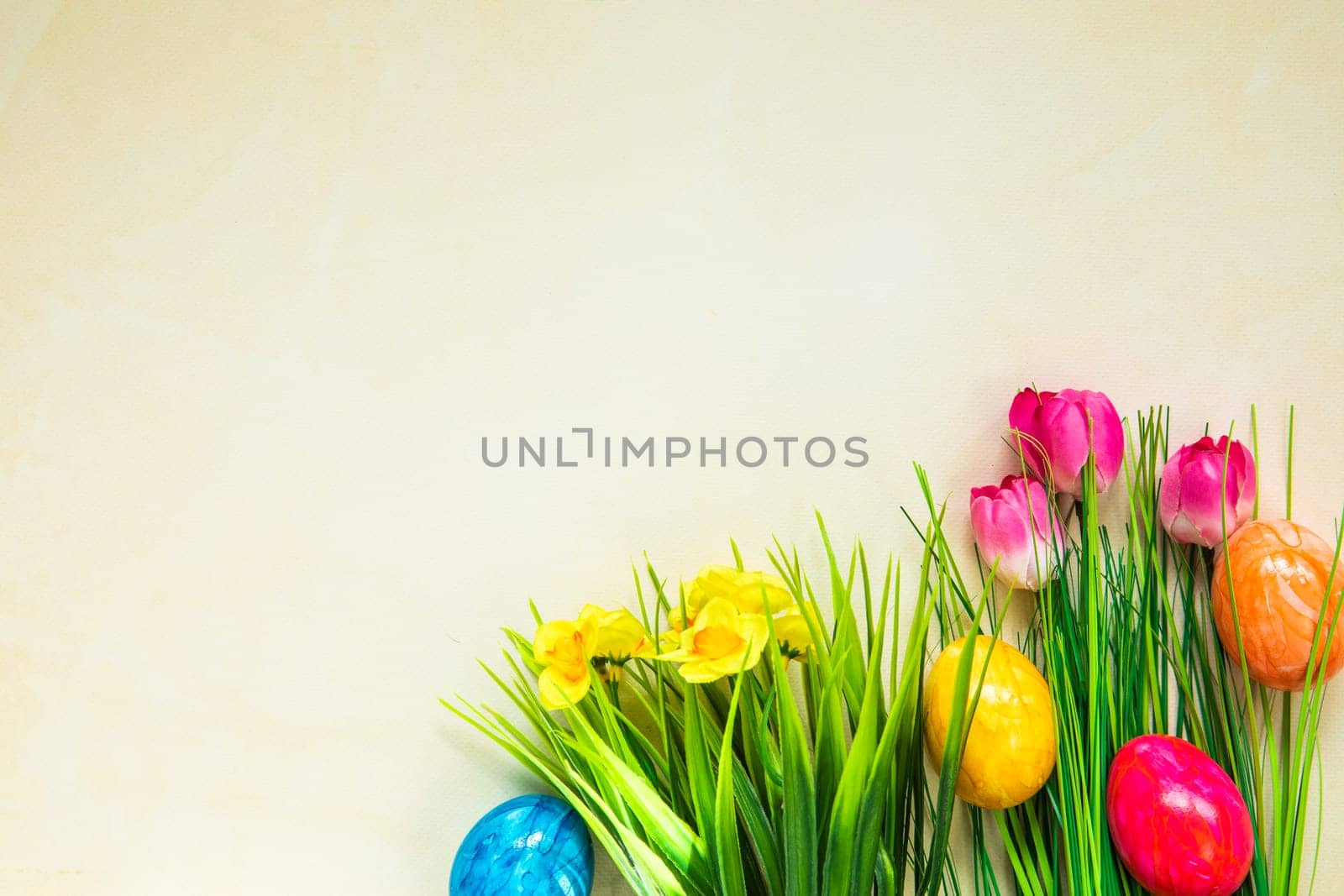 Colorful easter eggs with flowers and green grass. Easter eggs disappear on light yellow background. Easter Holiday, egg hunting concept top view