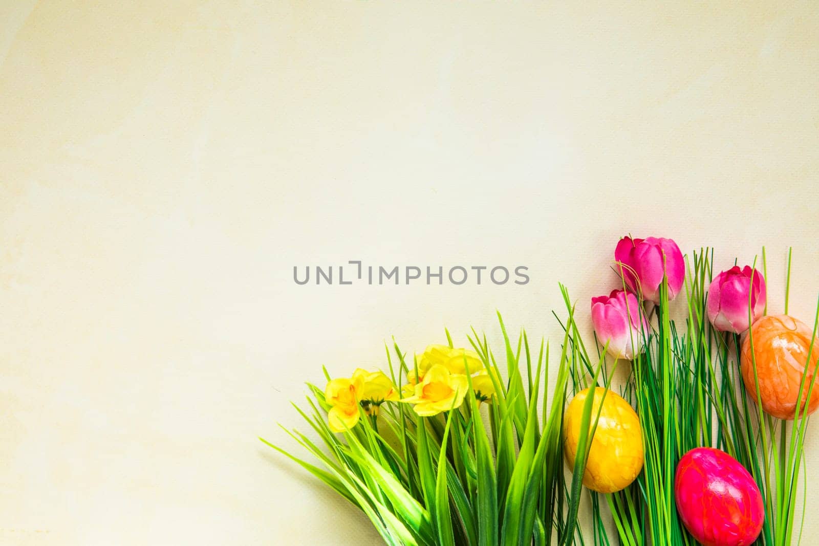 Colorful easter eggs with flowers and green grass. Easter eggs disappear on light yellow background. Easter Holiday, egg hunting concept top view