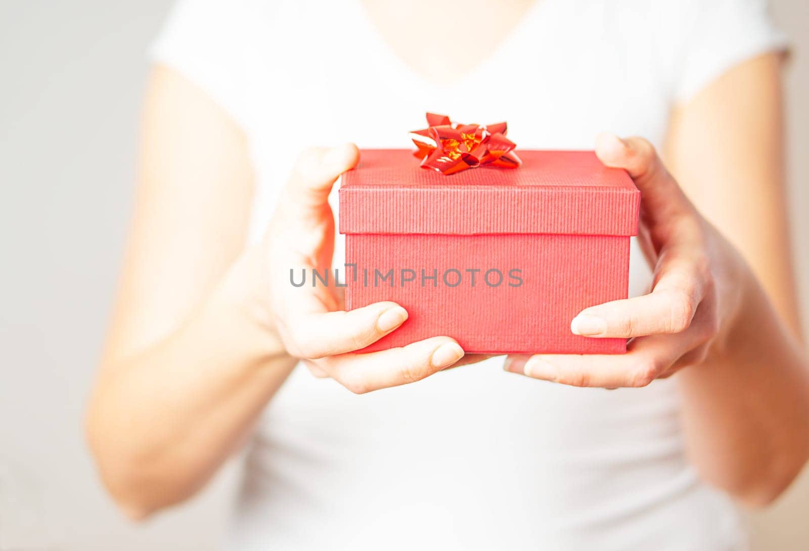 Female hands opening a small gift in a red box.