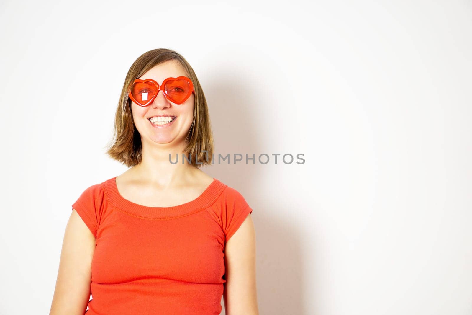 Portrait of a smiling young girl in a red sunglasses and a red shirt. Valentines day. High quality photo.
