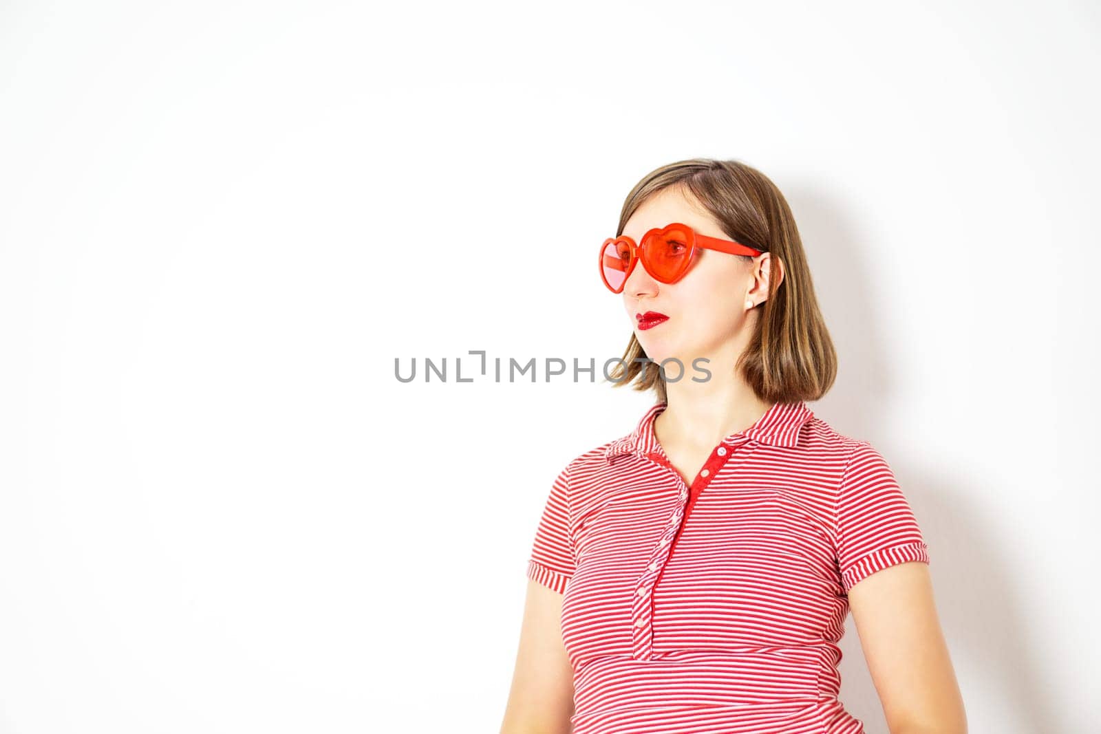 Portrait of the young beautiful woman with red heart sunglasses on the white background. by tanjas_photoarts