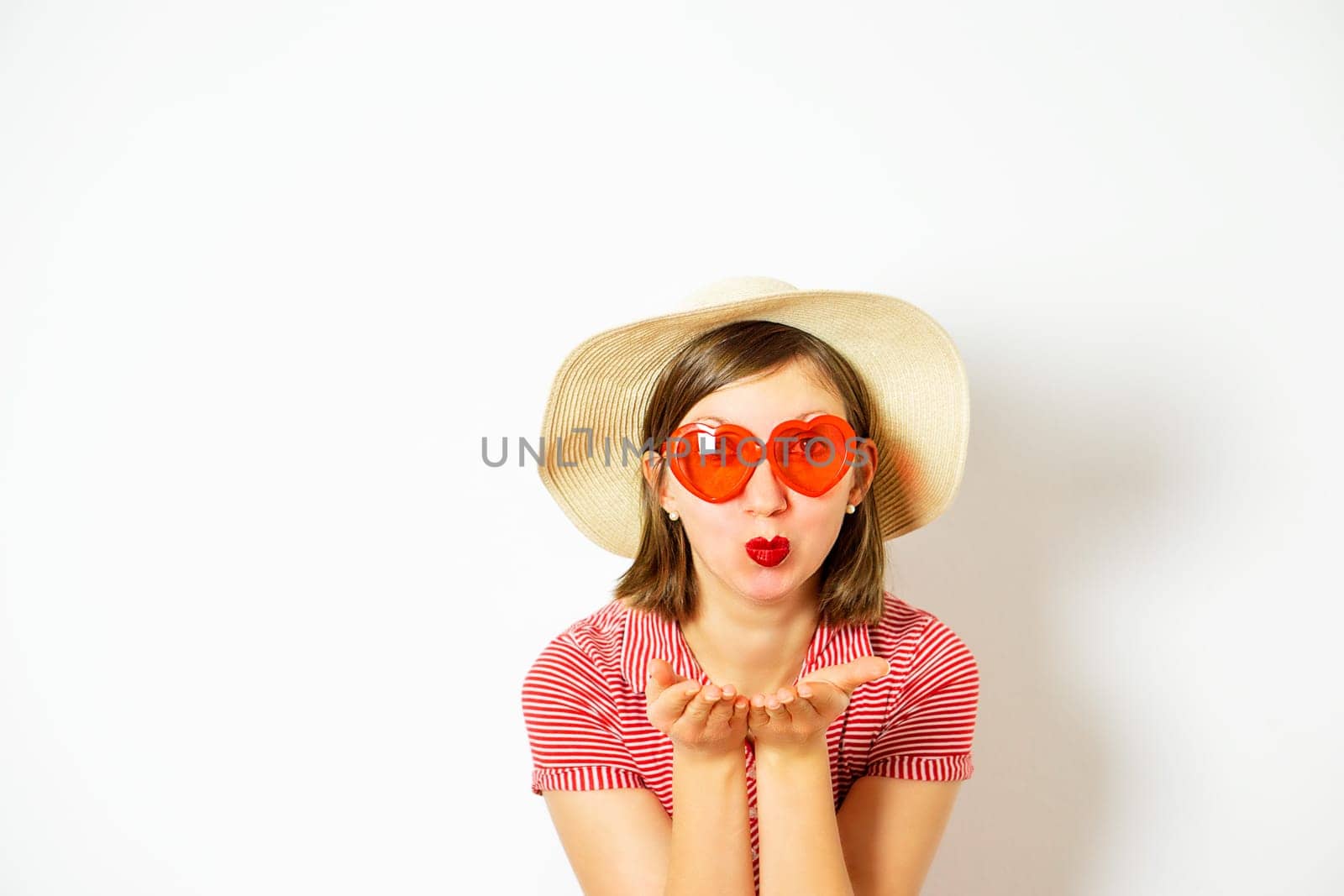 An attractive young girl with red sunglasses and summer hat sending an air kiss. Valentines day. by tanjas_photoarts