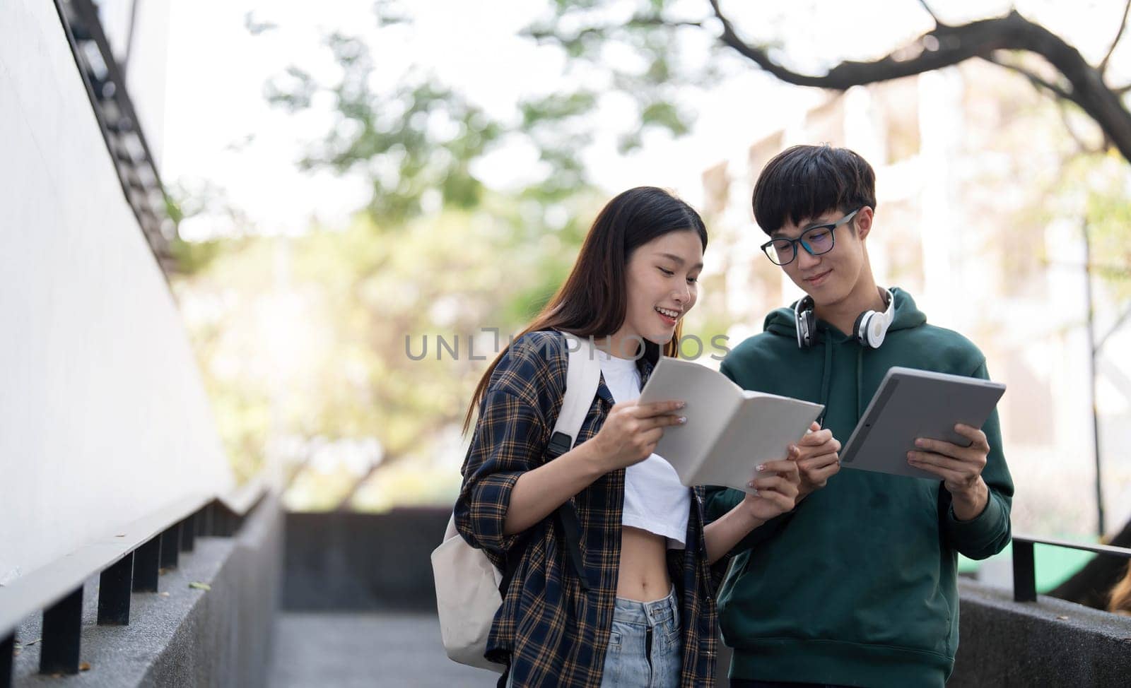 Group of Asian college student reading books and tutoring special class for exam on grass field at outdoors. Happiness and Education learning concept. Back to school concept. Teen and people theme...