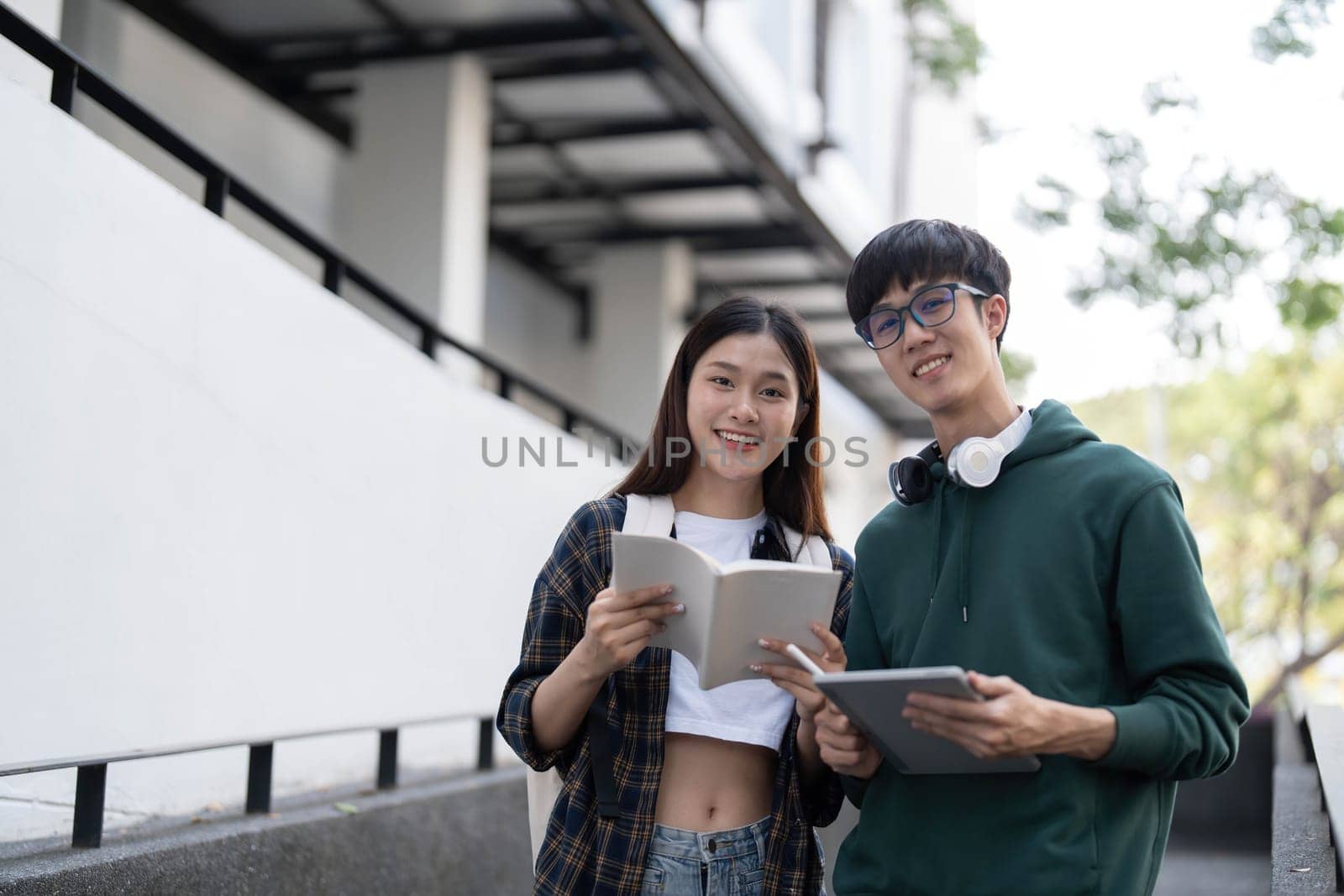 Group of Asian college student reading books and tutoring special class for exam on grass field at outdoors. Happiness and Education learning concept. Back to school concept. Teen and people theme. by wichayada