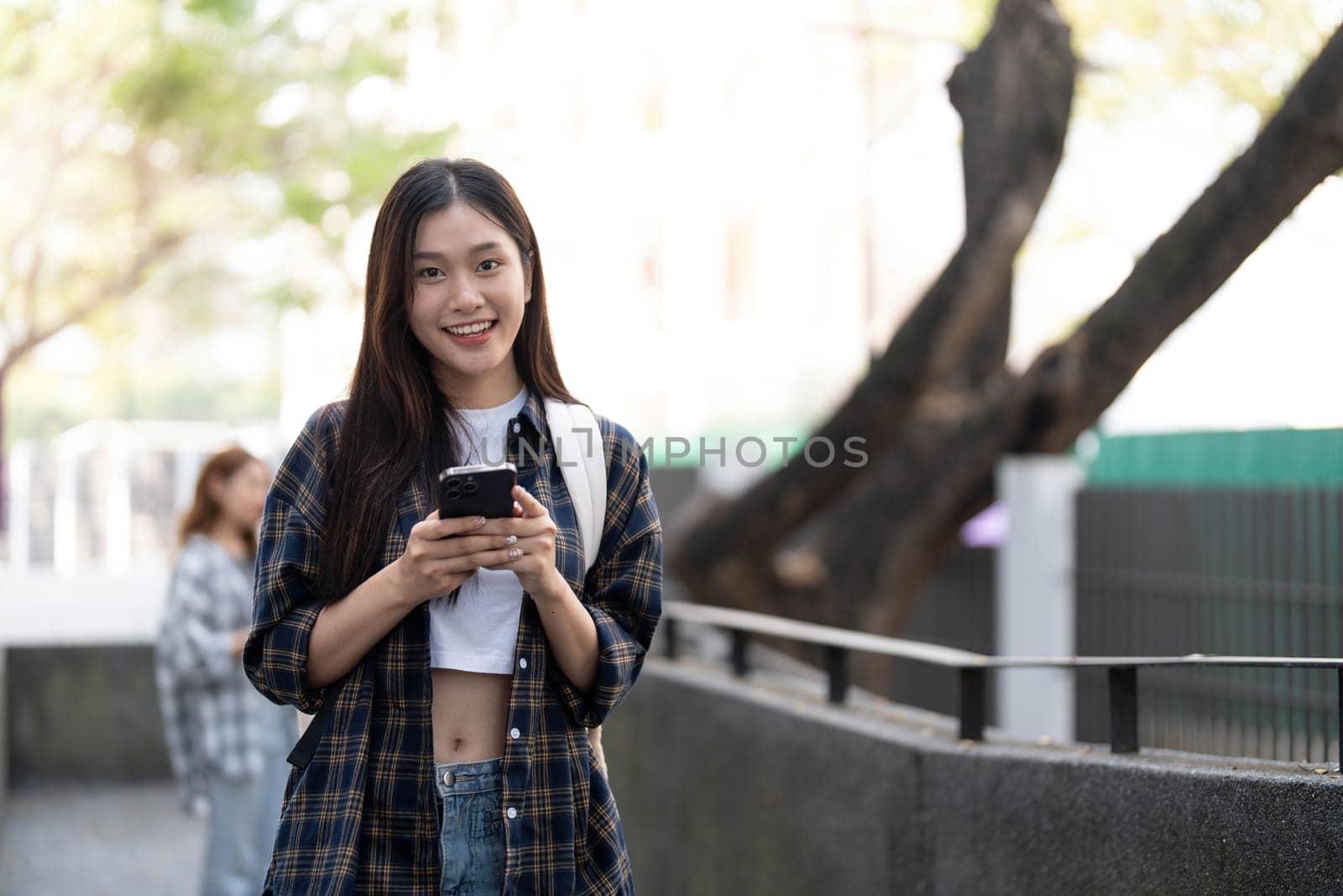 young happy attractive asian student smiling and looking at camera with friends on outdoor university background. Asian woman in self future education or personalized learning concept...