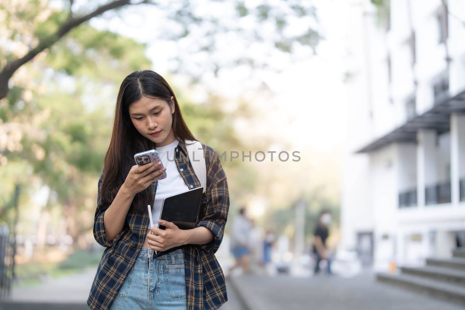 Female college students happily holding laptops outdoors after school on campus. when the sun goes down the horizon with warm light..
