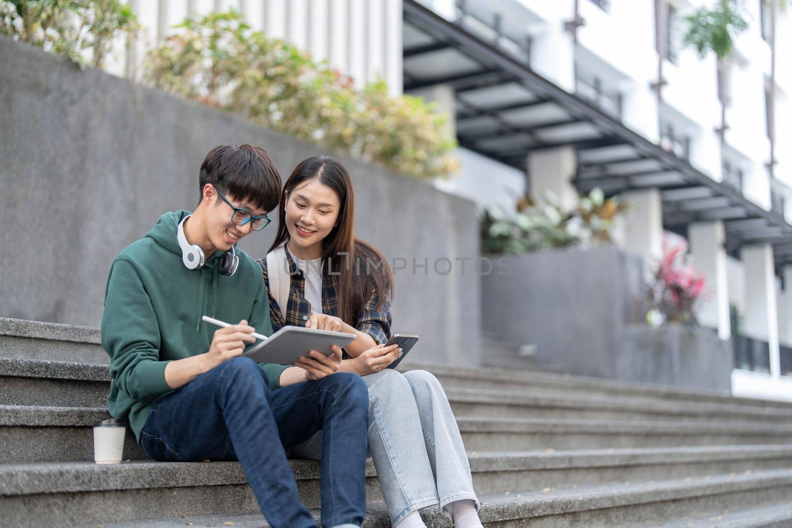 Group of Asian college student reading books and tutoring special class for exam on grass field at outdoors. Happiness and Education learning concept. Back to school concept. Teen and people theme...