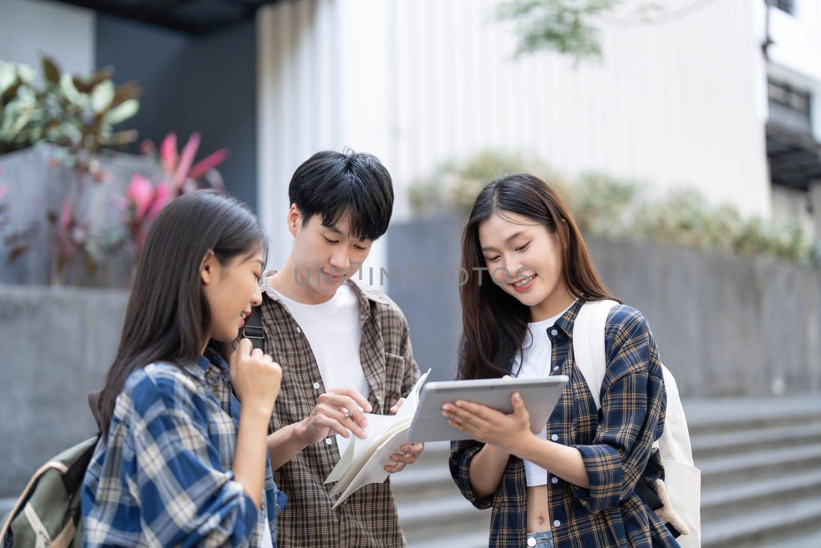 Group of Asian college student reading books and tutoring special class for exam on grass field at outdoors. Happiness and Education learning concept. Back to school concept. Teen and people theme...