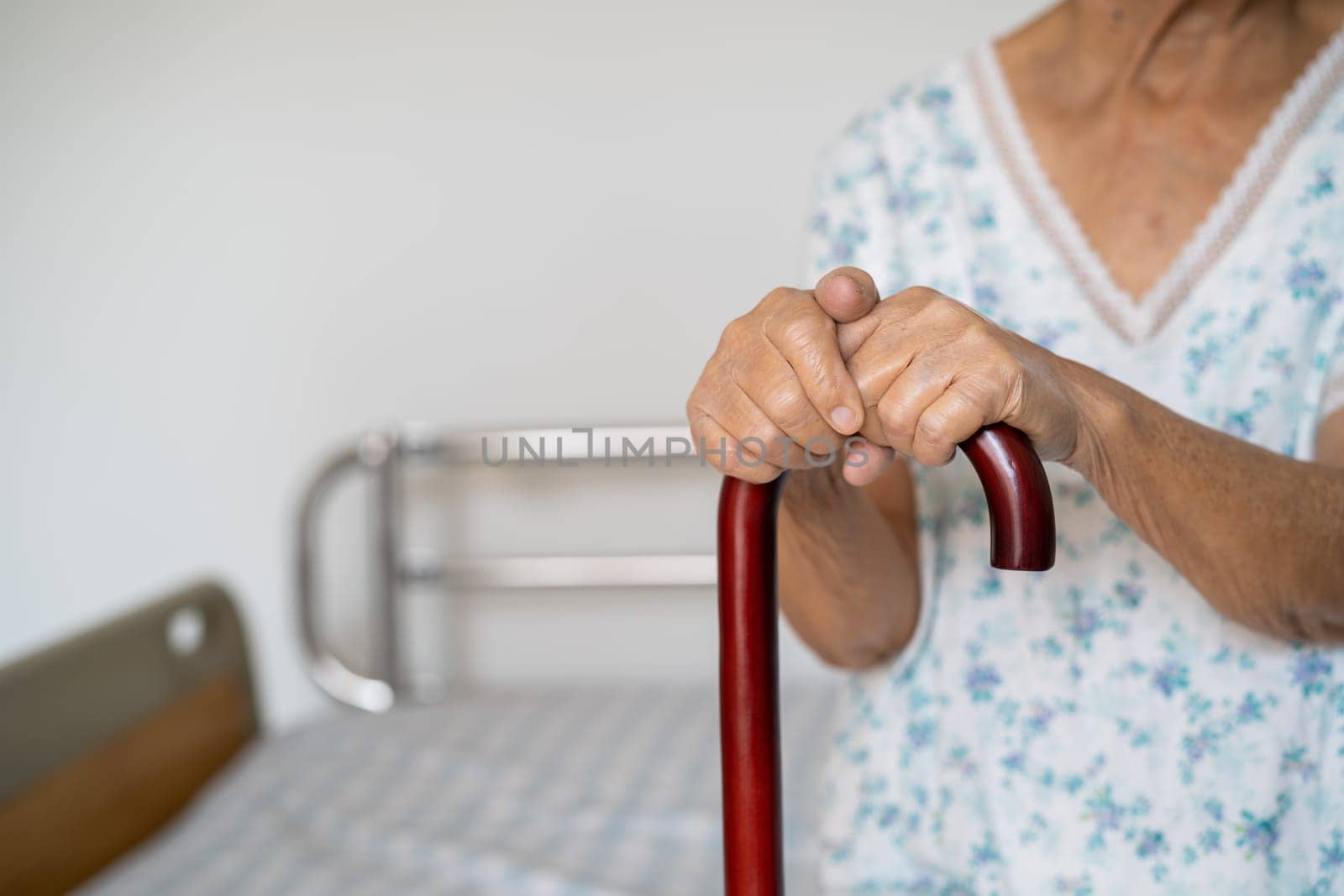 Asian elderly disability woman holding waling stick, wood cane, round handle, walking aid for help to walk. by pamai