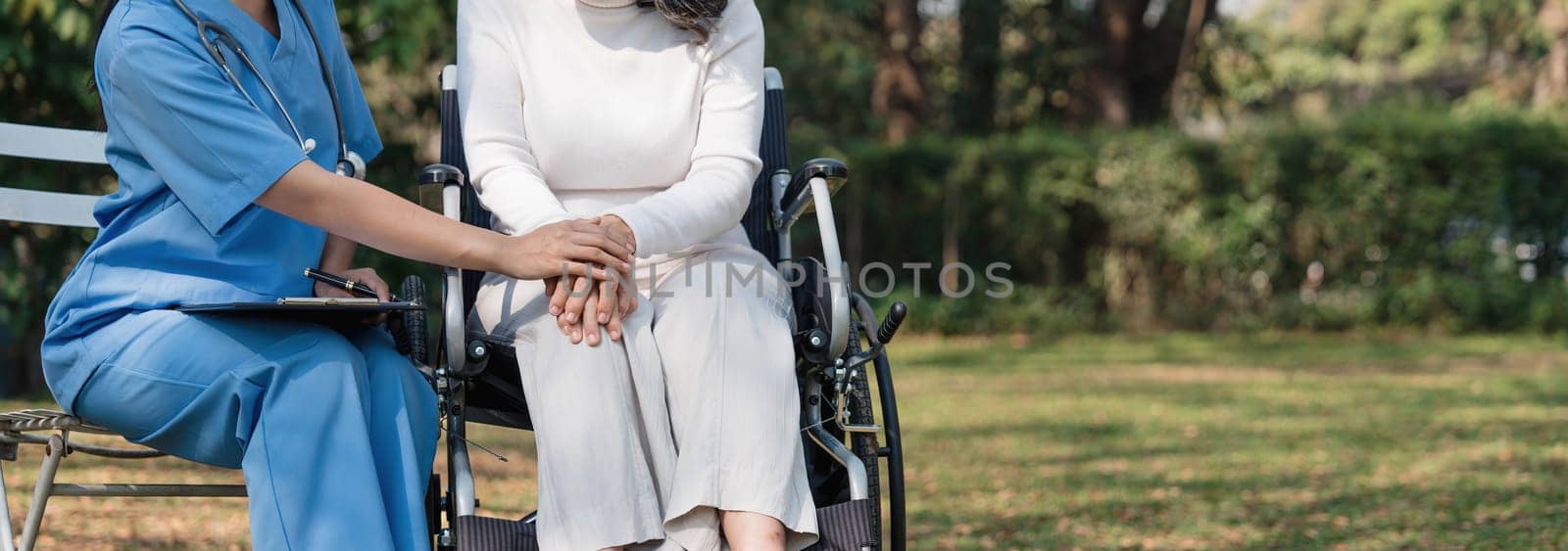 Close up happy patient is holding caregiver for a hand while spending time together outdoor...