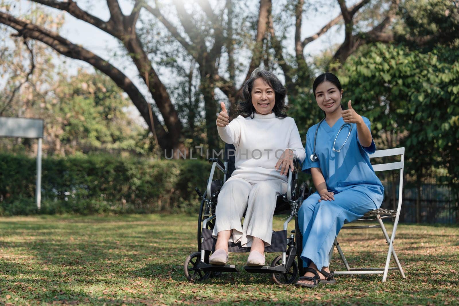 Female nurse doing blood pressure measurement of a senior woman patient. Doctor checking blood pressure of an elderly woman at garden home. Female caregiver and senior woman together