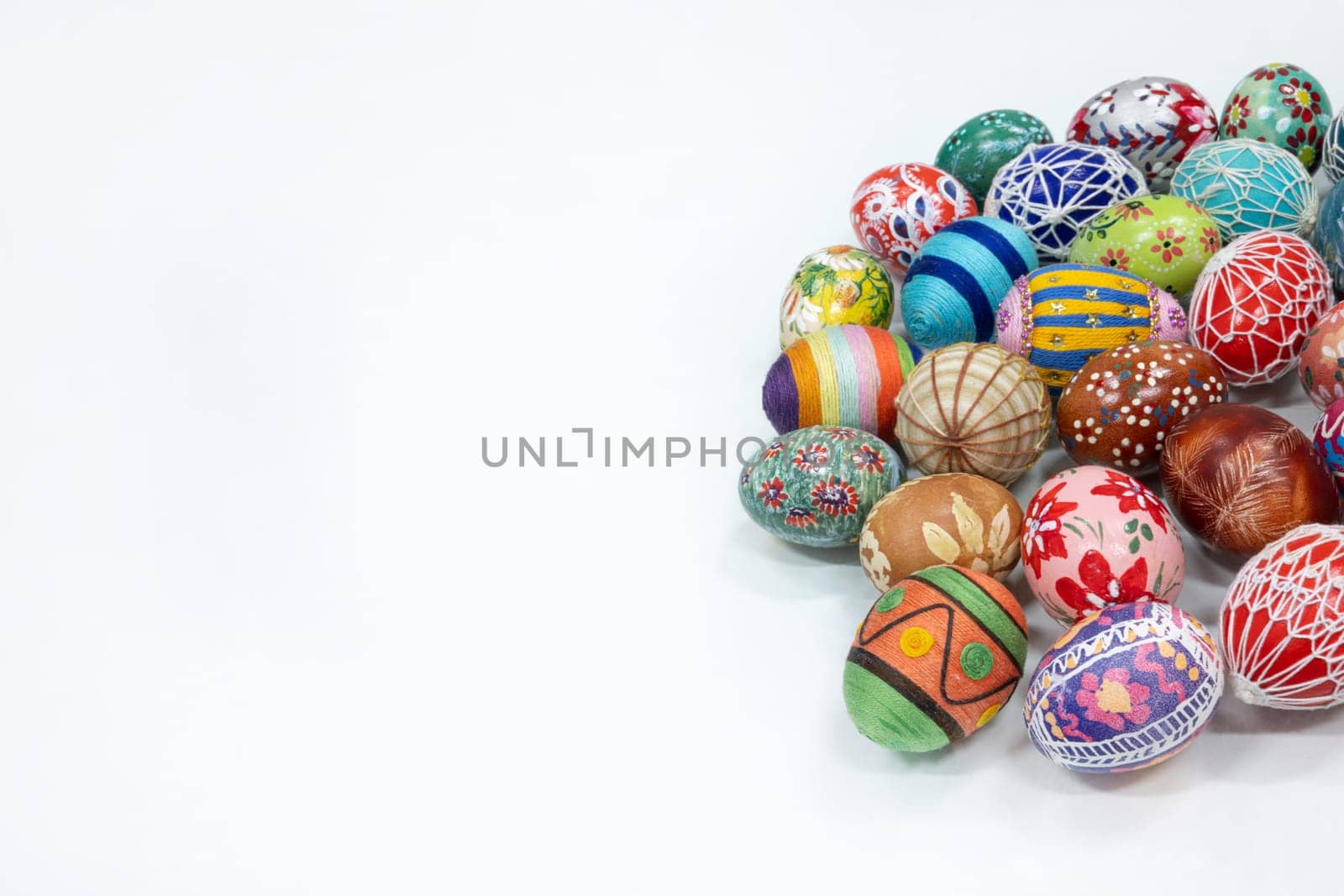 A simple Easter composition with a blank space to fill. Different colored traditional Easter eggs isolated from a white background lie side by side.