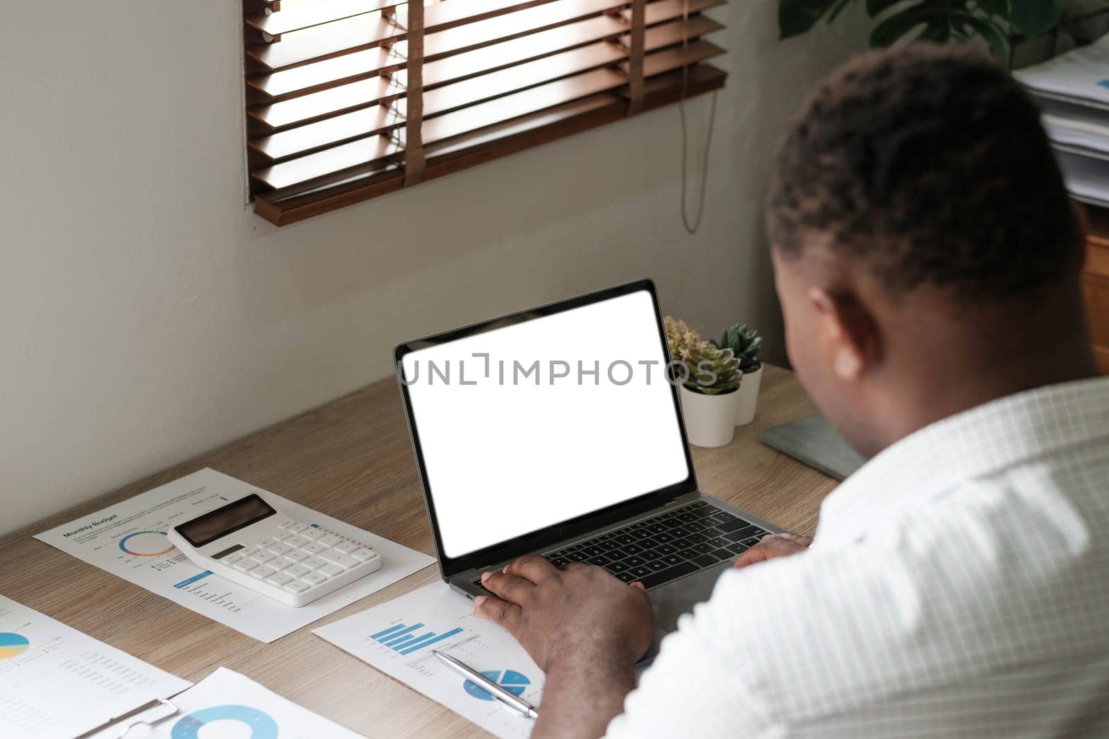 Mockup, blank screen laptop computer. Business man working on laptop computer on table at office. mock up for website design and digital marketing, over shoulder, rear view by wichayada