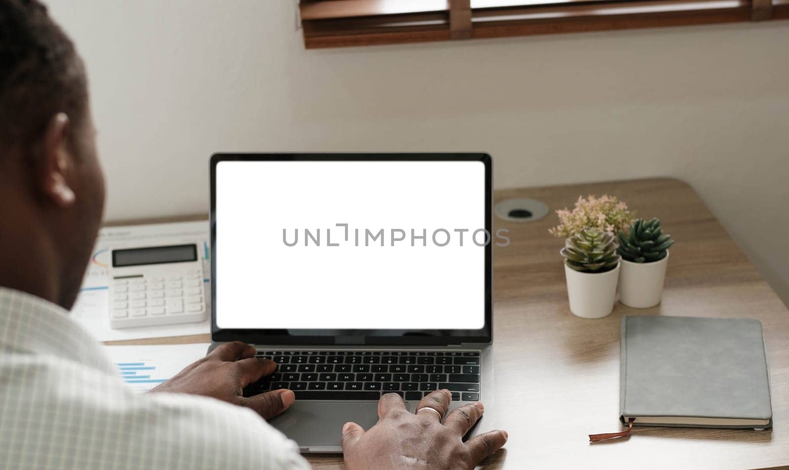 Mockup, blank screen laptop computer. Business man working on laptop computer on table at office. mock up for website design and digital marketing, over shoulder, rear view by wichayada