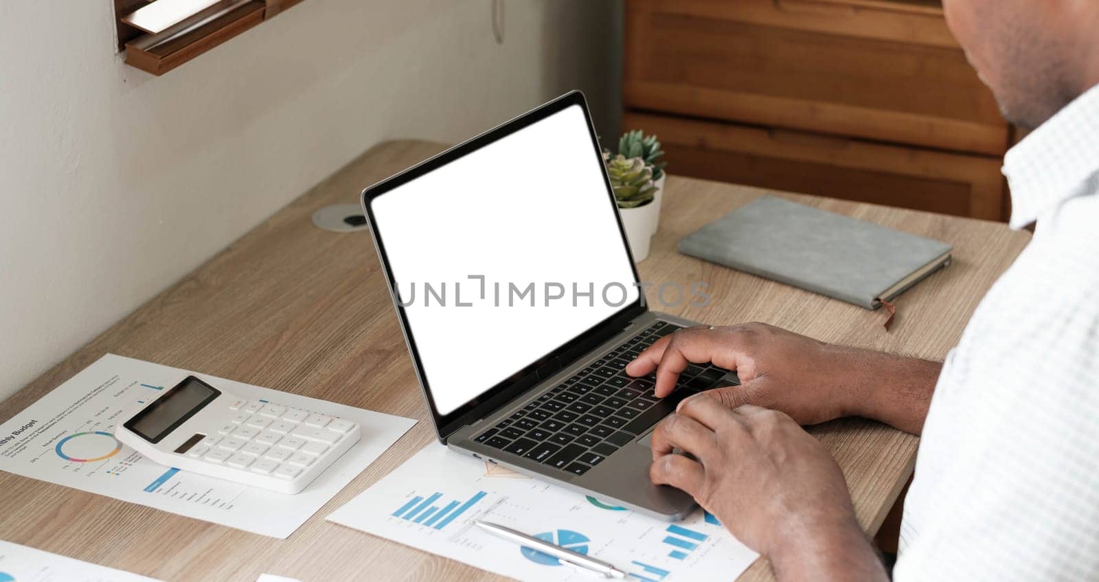 Mockup, blank screen laptop computer. Business man working on laptop computer on table at office. mock up for website design and digital marketing, over shoulder, rear view by wichayada