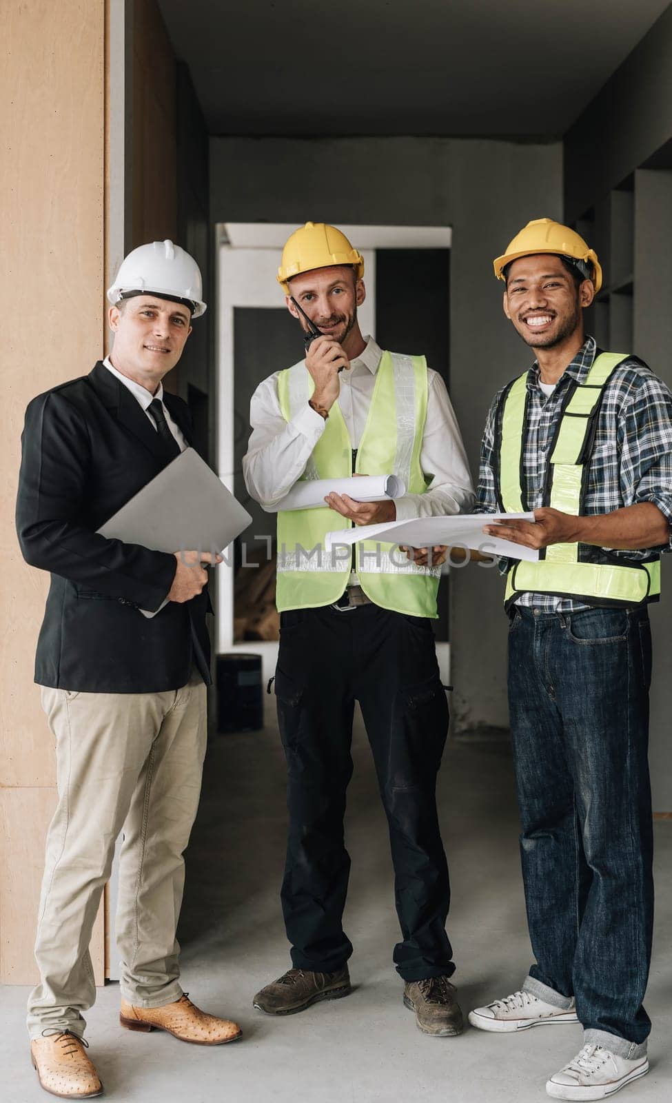 Civil engineer teams meeting working together wear worker helmets hardhat on construction site in modern city. Foreman industry project manager engineer teamwork. Asian industry professional team. by wichayada