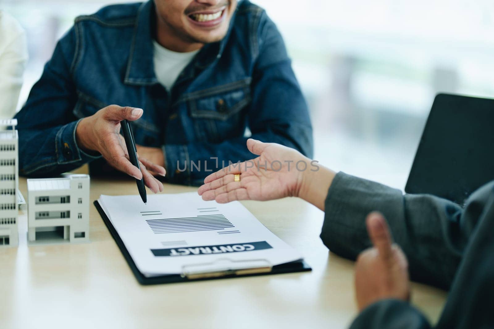 Guarantee Insurance Sign a contract, couple a smiling couple is signing a contract to invest in real estate with the Mortgage officer with the bank by Manastrong