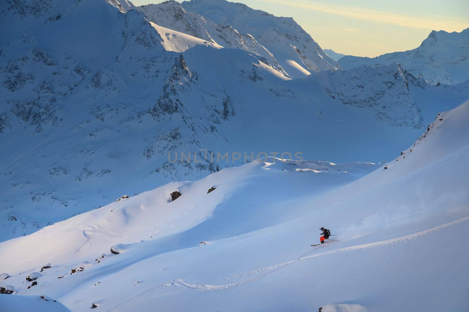 Freerider skier down the powder snow at sunset, italian alps. Skier at ski resort off-piste, colorful winter sunset by yanik88