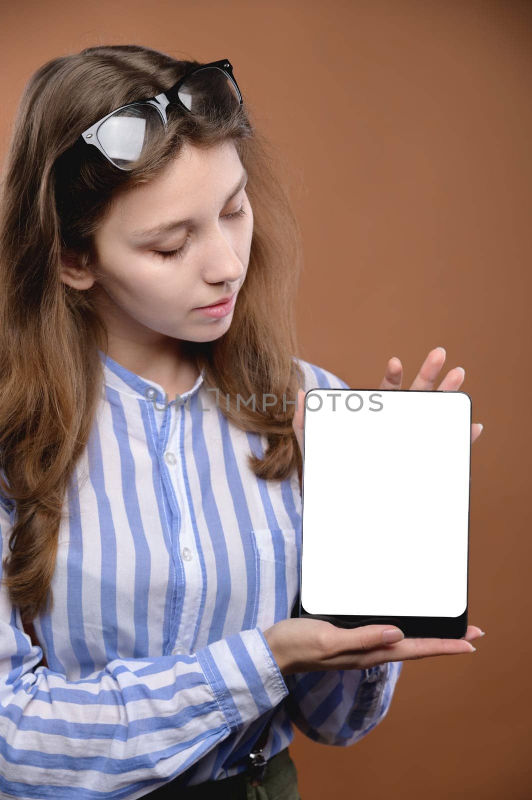 woman showing tablet computer screen smiling with glasses. Portrait of a cheerful confident cool girl holding a tablet advises to choose a new gadget on a bright color background by yanik88