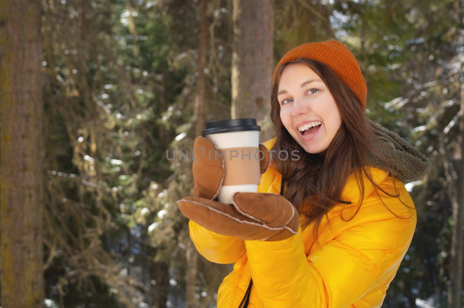 people, hot drinks and leisure concept. happy woman drinking takeaway coffee in winter outdoors showing her glass to camera by yanik88