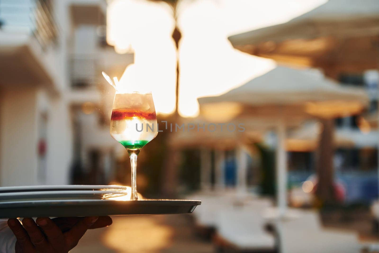 Close up view of drink. Black waiter in formal clothes is at his work outdoors at sunny daytime.