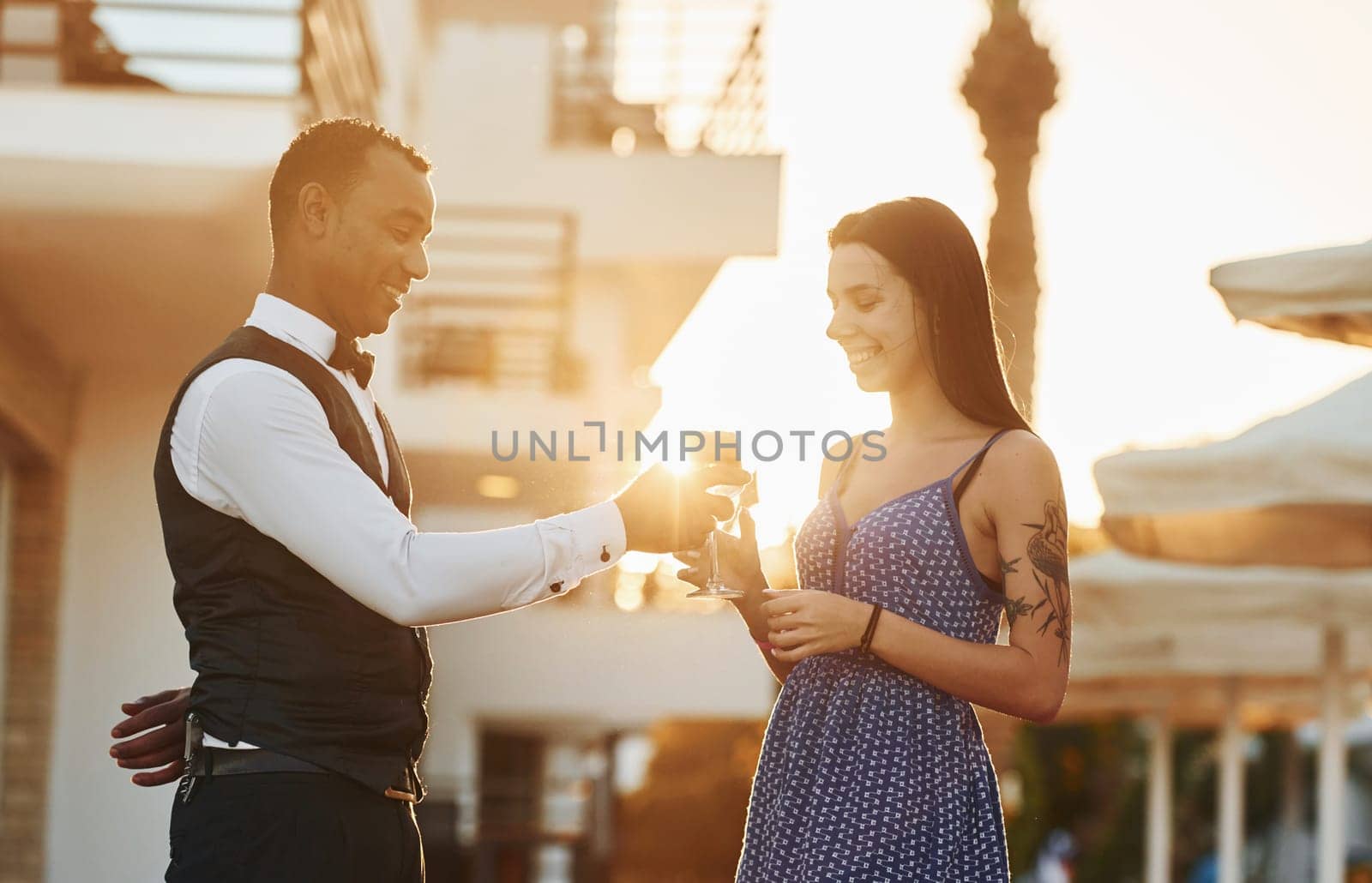Order for woman. Black waiter in formal clothes is at his work outdoors at sunny daytime.