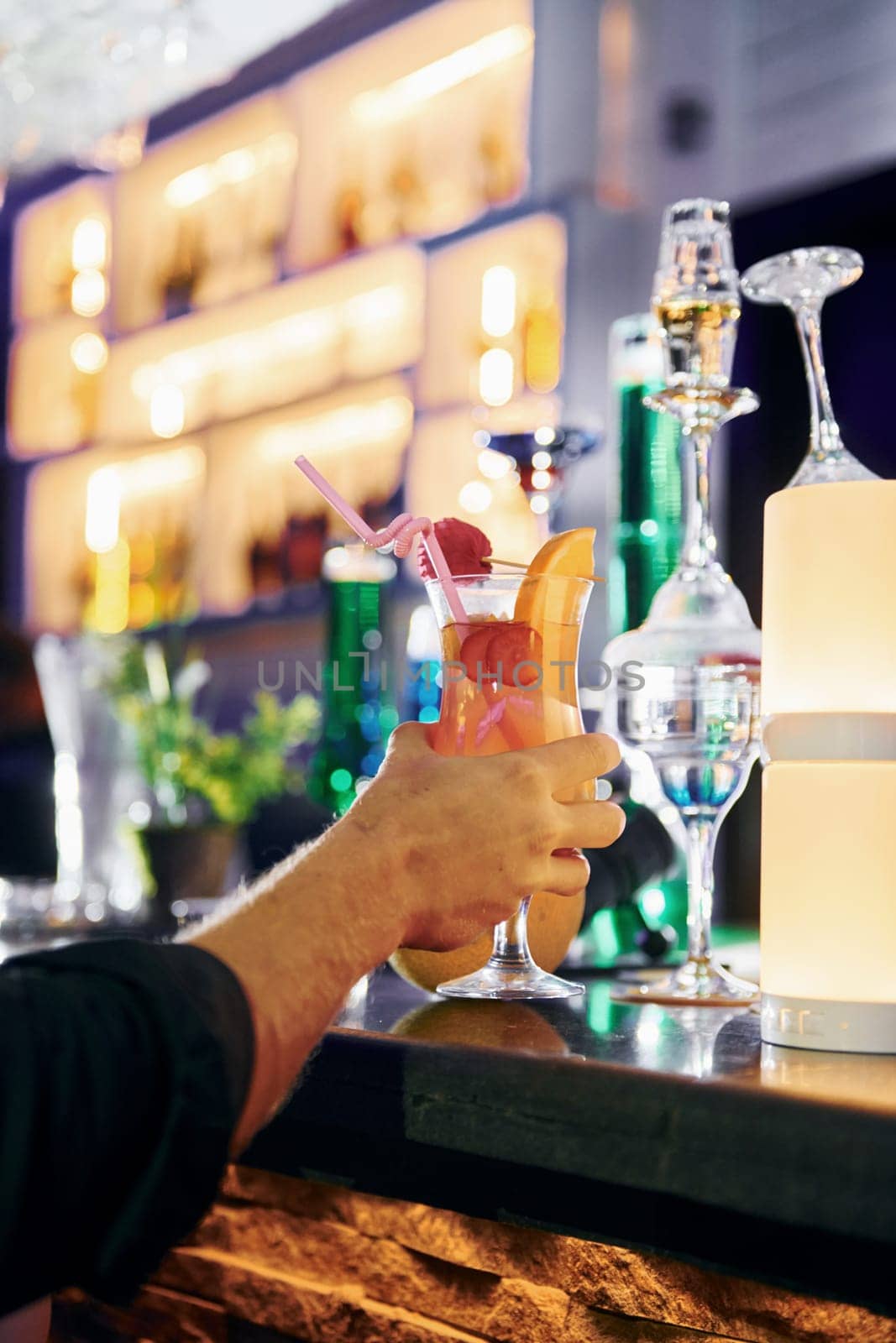 Close up focused view of man's hand that holds cocktail.