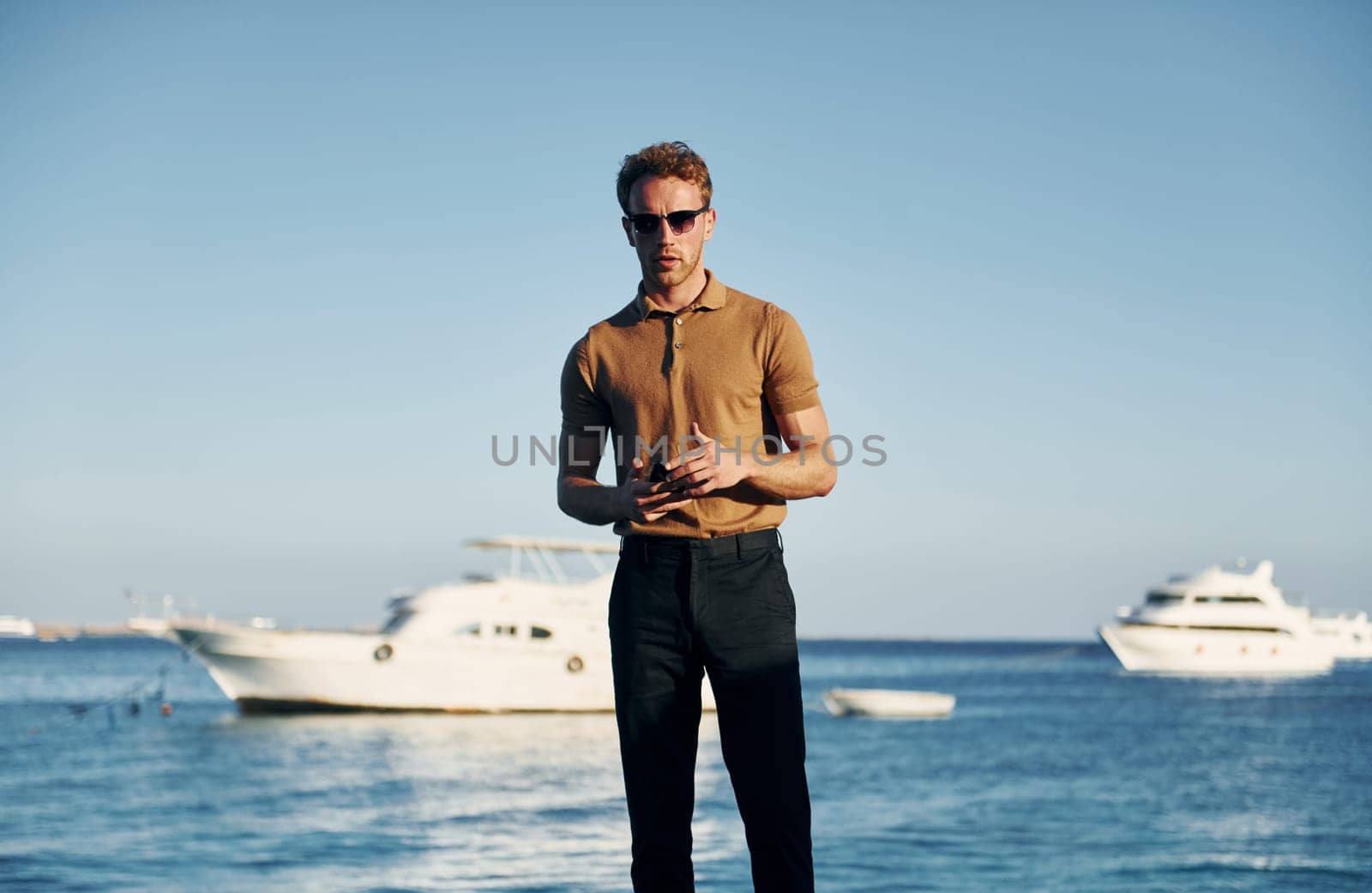 In sunglasses. Young man is outdoors at sunny daytime. Concept of vacation.