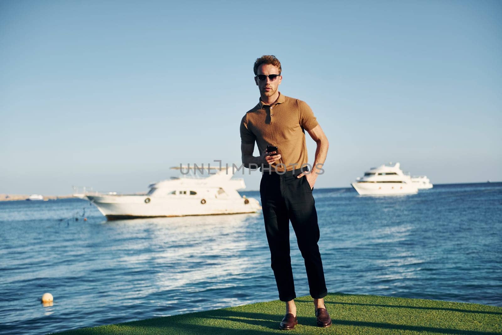 In sunglasses. Young man is outdoors at sunny daytime. Concept of vacation.