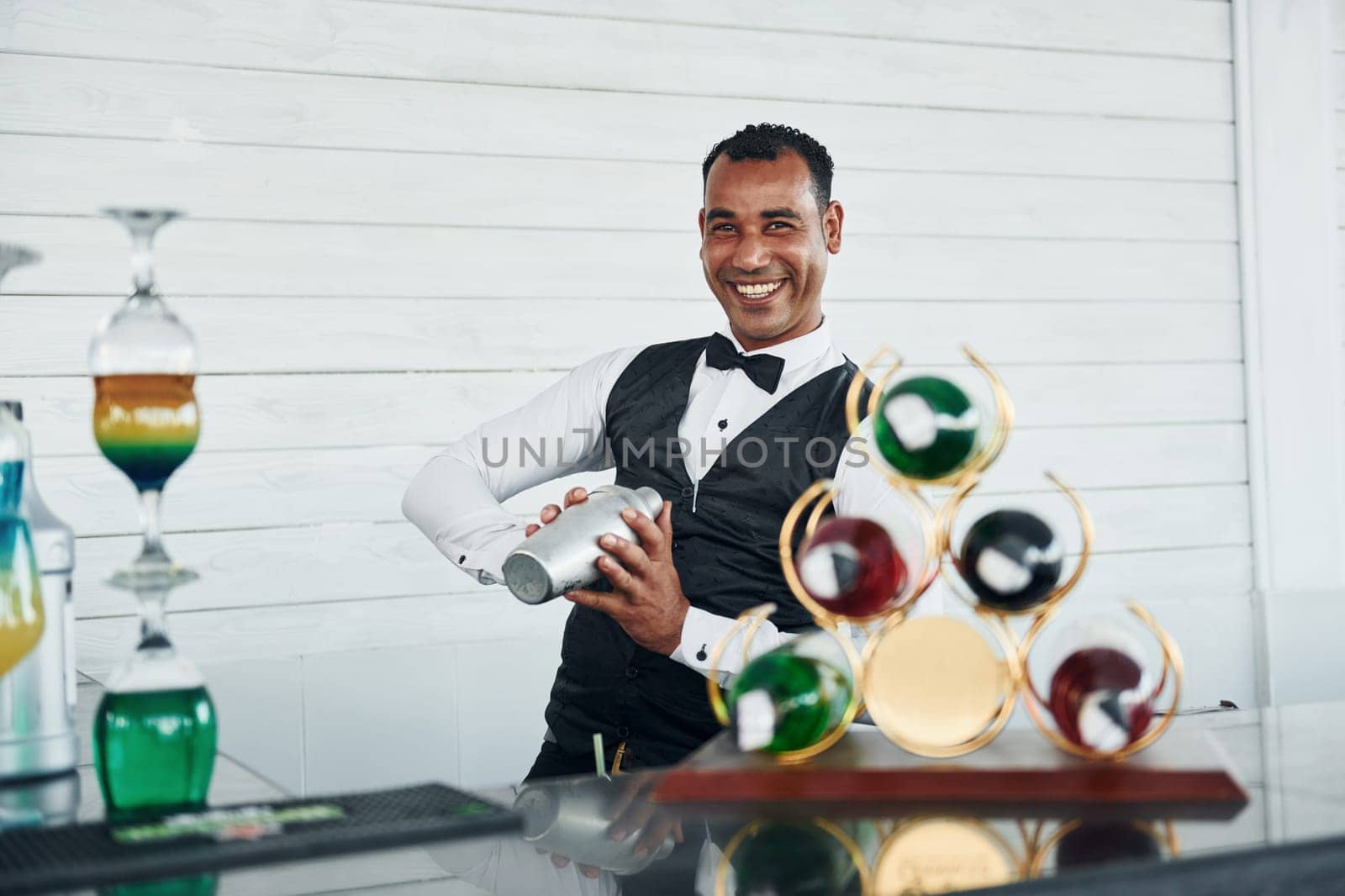 At the bar. Black waiter in formal clothes is at his work outdoors at sunny daytime.