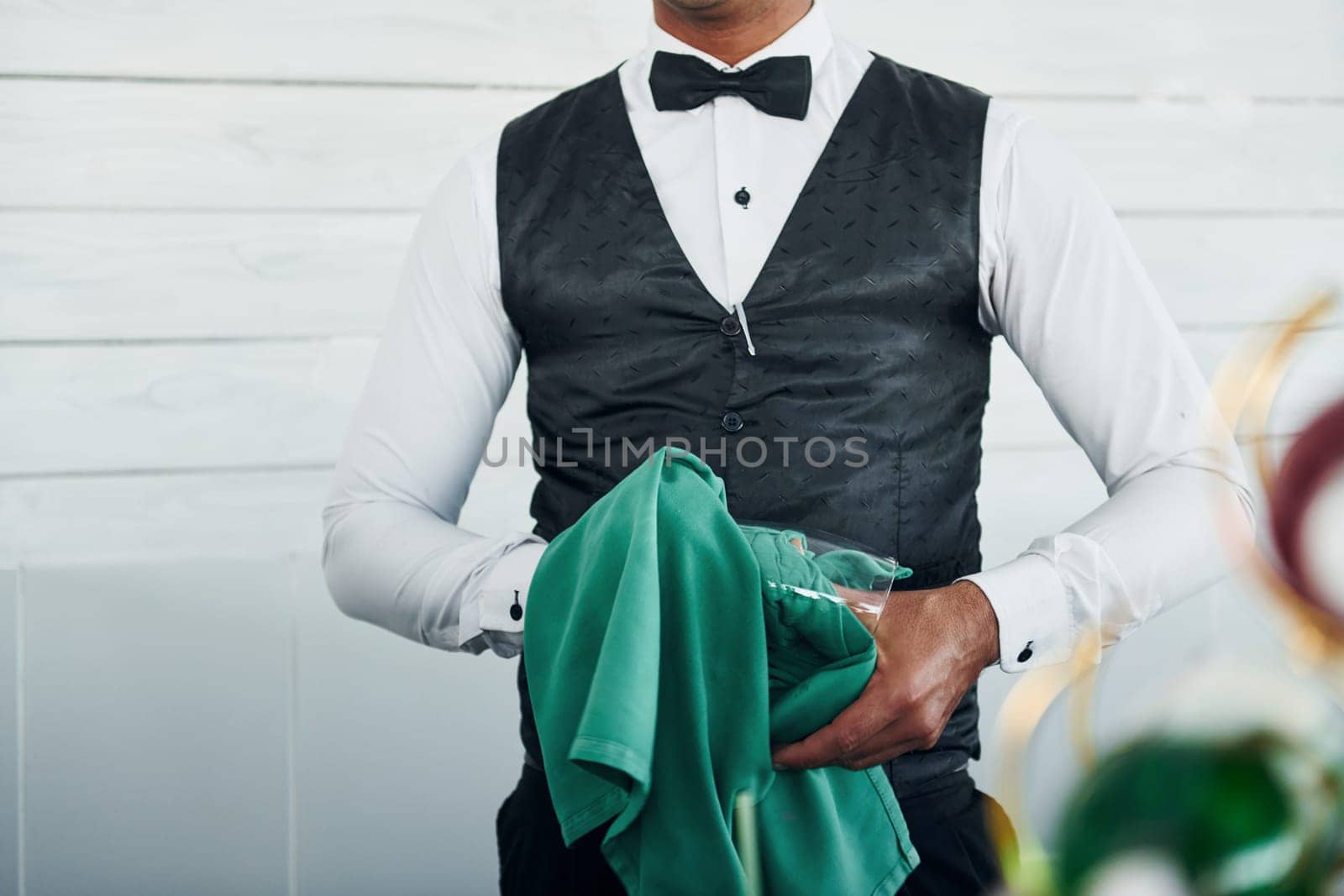 Black waiter in formal clothes is at his work outdoors at sunny daytime.